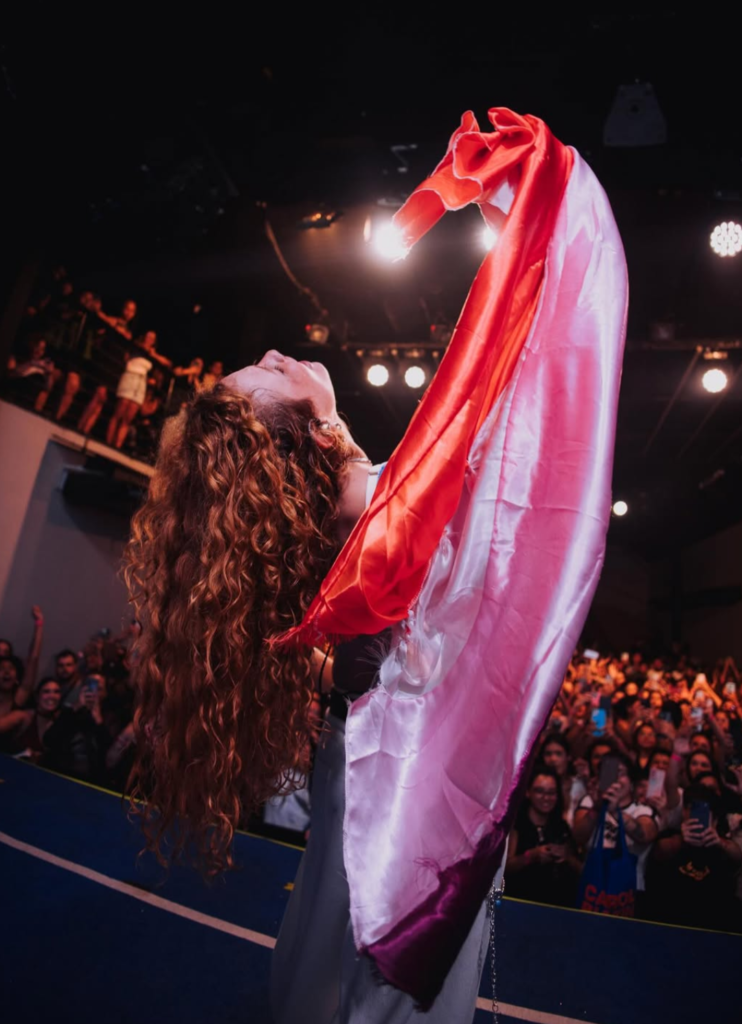 Carol Biazin com a bandeira lésbica durante show. Imagem: Iris Alves/ Divulgação
